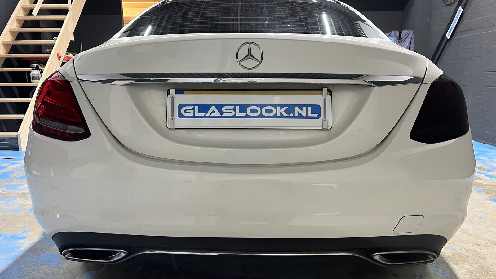 Witte Mercedes met een standaard en een donker gesmookt achterlicht naast elkaar